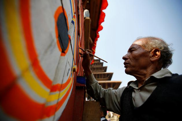 An artist paints on the giant wheel of the chariot of God Bhairab. (Navesh Chitrakar/REUTERS)