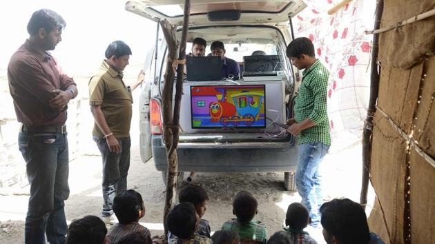 A TV screen displays cartoons at the 'Zero Connect' Programme with a group of children of salt pan workers during a tent school workshop using an Internet-connected van. (AFP)