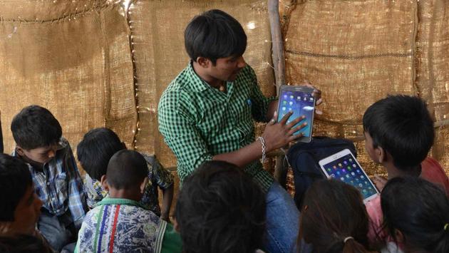 Anand Solanki (C), facilitator of the 'Zero Connect' programme scrolls through a tablet with a group of children of salt pan workers during a tent school workshop using an Internet-connected van, in the Little Rann of Kutch. (AFP)