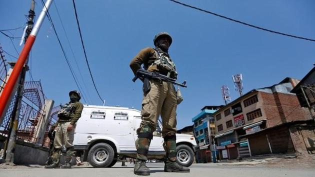 Policemen guard a deserted street during restrictions in downtown Srinagar.(Reuters Photo)
