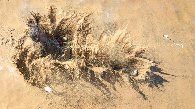A participant in the 3rd extreme ‘ La Barjot Run’ runs into the water . (Martial Trezzini/Keystone / AP)