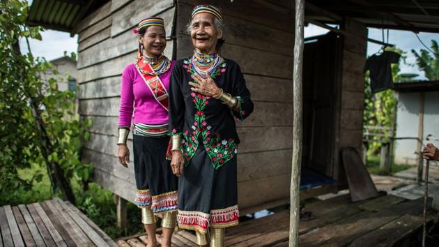 Anyu Daik (R), 70, and Anat Ugom, 44 (L), from a sub-tribe of the Bidayuhs indigenous group wearing traditional yellow copper rings called ‘rasung’ on their calves, ‘ ruyang’ on their forearms and ‘tumbih’ as necklaces as they stand outside their kitchen in Padawan in the state of Sarawak on the island of Borneo. (Mohd RASFAN / AFP)