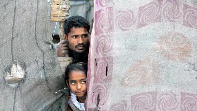 A Rohingya Muslim along with his daughter peeps from a damaged door at a refugee camp. J&K has several charities that help the Rohingya Muslims.13,400 Myanmarese and Bangladeshi migrants are living in camps in Jammu and Samba. (Nitin Kanotra/HT Photo)