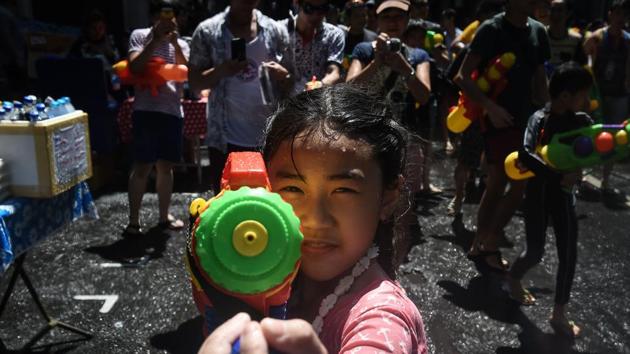 A girl aims a water pistol at the camera during Songkran, Thailand's traditional New Year festival, on Silom road in Bangkok. (AFP)