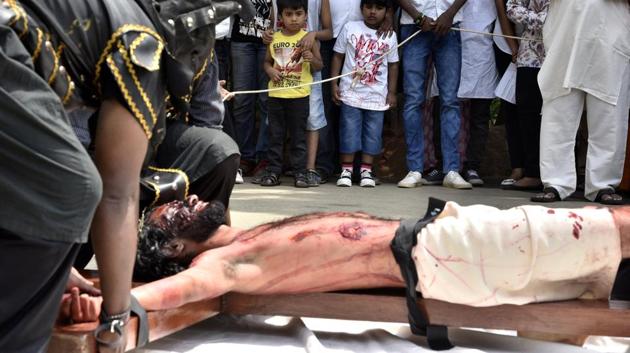 Children watching as artist enacts the crucifixion of Jesus on the occasion of Good Friday at Our Lady Lourdes Church at Cambridge Layout in Bengaluru. (Arijit Sen/HT Photo)