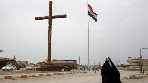 A woman walks past a big cross at the entrance of the town of Qaraqosh. Shi’ites in the Iraqi government forces and paramilitary groups, mostly from further south in the country, has scribbled such slogans on buildings all over Mosul too. Soldiers have also hoisted the flag of Ali in the city and on their on military vehicles. (Marko Djurica/Reuters)