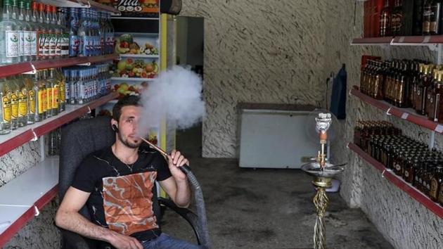 Steve Ibrahim, an alcohol shop owner, smokes in the town. Supermarkets and restaurants remain closed in Qaraqosh, with windows smashed and burnt furniture strewn across floors. One of the few businesses to have reopened is Steve Ibrahim’s alcohol shop in the town centre; in the absence of cafes it has become a meeting point for local people. (Marko Djurica/Reuters)
