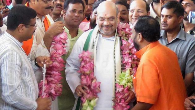 Odisha BJP president Basanta Panda and senior leader KV Singhdeo welcome Amit Shah with a garland of 74 lotuses on his arrival at the airport in Bhubaneswar.(PTI Photo)