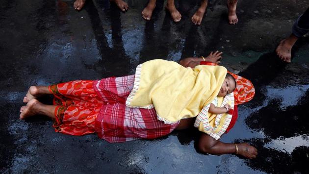 An infant lies on the back of a woman as she performs a ritual while worshipping Sheetala Mata, the Hindu goddess of smallpox, during Sheetala Puja in which people pray for the betterment of their family and society, in Kolkata, April 15, 2017. (Rupak De Chowdhuri / REUTERS)
