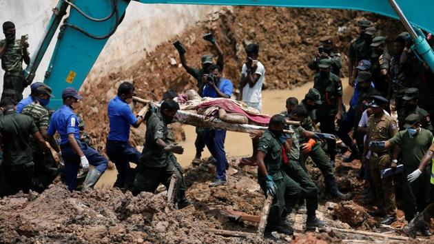 Members of the military carry a dead victim during a rescue mission after a garbage dump collapsed and buried dozens of houses in Colombo. (Dinuka Liyanawatte / REUTERS)