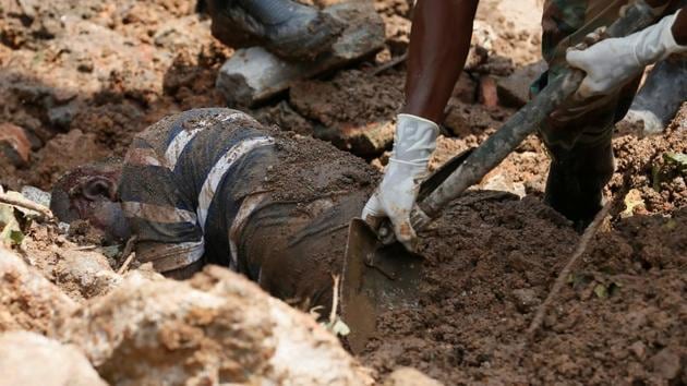 Members of the military dig out the body of a dead victim during a rescue mission after a garbage dump collapsed and buried dozens of houses in Colombo, Sri Lanka . (Dinuka Liyanawatte / REUTERS)