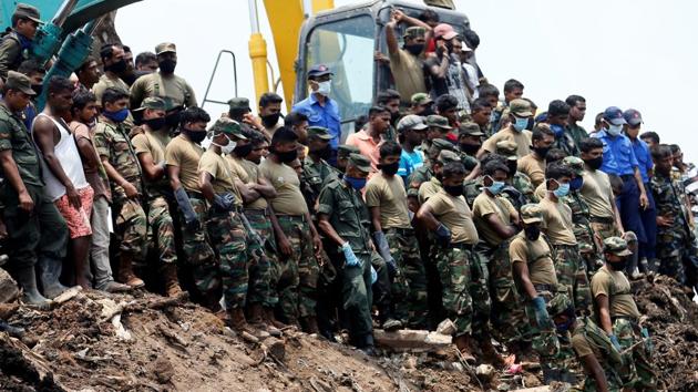 Members of the military wait until another rescue team recovers a dead victim during a rescue mission. (Dinuka Liyanawatte / REUTERS)