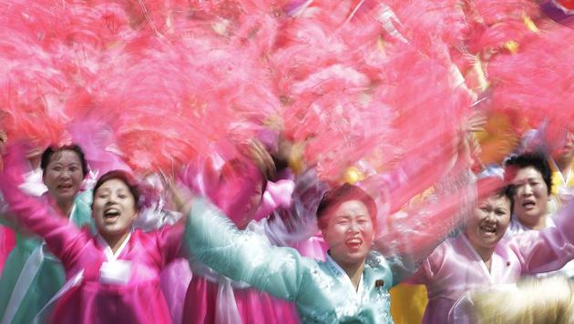 North Korean women wave and cheer as they look toward their leader Kim Jong Un during a military parade. (Wong Maye-E / AP)