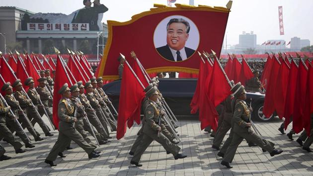 North Korean soldiers carry flags and a photo of late leader Kim Il Sung as they march across Kim Il Sung Square during a military parade. (Wong Maye-E / AP)