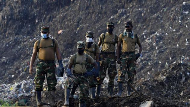 Sri Lankan military personnel stand among damaged homes at the site of a collapsed garbage dump. (ISHARA S. KODIKARA / AFP)