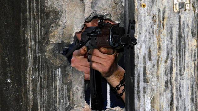 A member of the joint Palestinian security takes position through a hole in a wall with a kalashnikov assault rifle in Ain al-Hilweh camp, Lebanon's largest Palestinian refugee camp, near the southern coastal city of Sidon, on April 12, 2017, after clashes that took place earlier in the week between an extremist group and the security force. Fighting erupted on April 7, 2017 after Palestinian factions deployed throughout the camp as part of a joint security force aimed at combatting the influence of a local Islamic extremist group. Ain al-Hilweh, which houses 61,000 Palestinians, is home to multiple armed factions and has been plagued by intermittent clashes among them as well as against smaller extremist groups. Lebanon's army does not enter Palestinian refugee camps, where security is managed by joint committees of Palestinian factions. (AFP)