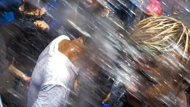People dance to blasting DJ house music under the spray of water hoses in a street of Yangon on April 13, 2017 while celebrating the Buddhist New Year or Thingyan as it is known locally. The four southeast Asian nations of Myanmar, Thailand, Cambodia and Laos started the Buddhist new year, known as Thingyan in Myanmar and Songkran in Thailand, on April 13. (ROBERTO SCHMIDT / AFP)