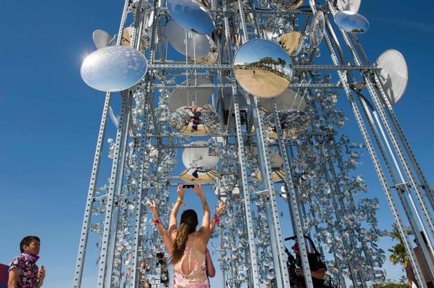 Visitors take selfies in front of his piece ‘Lamp Beside the Golden Door’ during the Coachella Valley Music And Arts Festival. (VALERIE MACON / AFP)