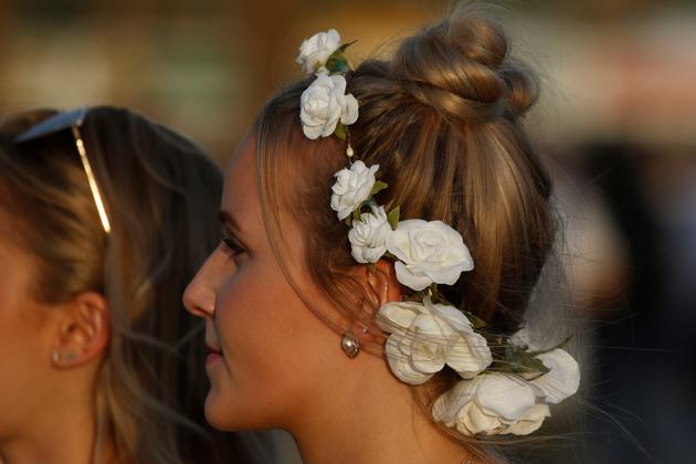 A woman walks with flowers in her hair in the late afternoon sun during the Coachella Valley Music and Arts Festival. (Carlo Allegri / REUTERS)