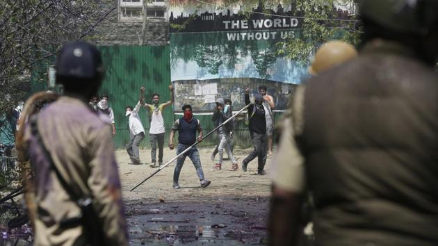 A Kashmiri student holds an iron rod as others throw stones at policemen as they clash in Srinagar on Monday.(AP) A Kashmiri student holds an iron rod as others throw stones at policemen as they clash in Srinagar on Monday.(AP)