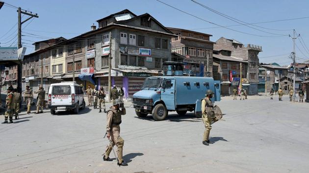 Police and CRPF personnel stand guard during restrictions imposed by the government authorities and strike call given by Hurriyat Conference following the killing of a youth, in Batamaloo. (S Irfan / PTI)