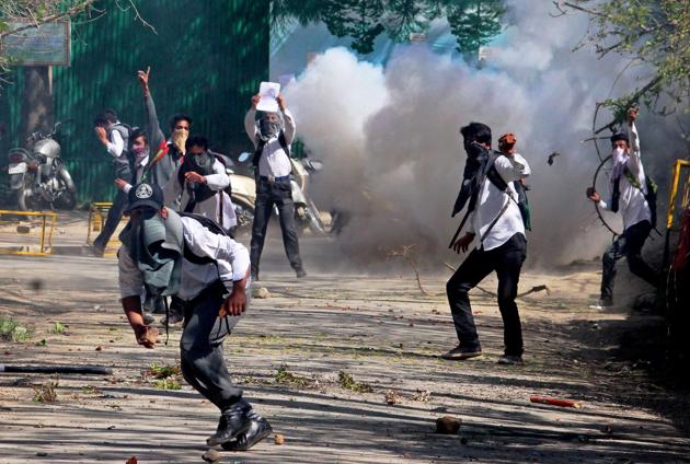 Student throwing stones on police amid heavy tear smoke during a clash with police outside SP college in the vicinity of Lal Chowk in Srinagar on Monday. The students’ protest prompted the government to shut down colleges for two days.(PTI)