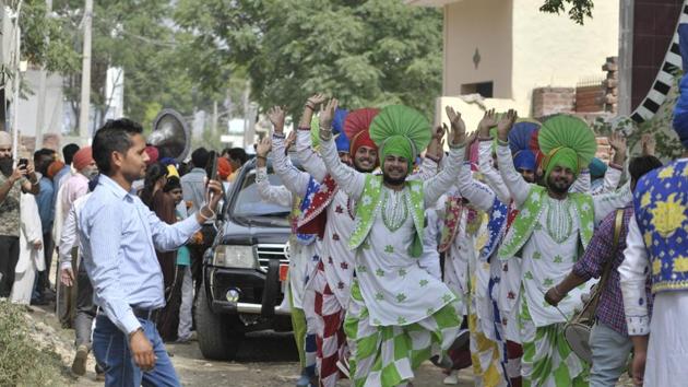 College students of the village performing bhangra in front of the cavalcade of Canadian defence minister to welcome him in Bombeli village. (Ravi Kumar/HT)