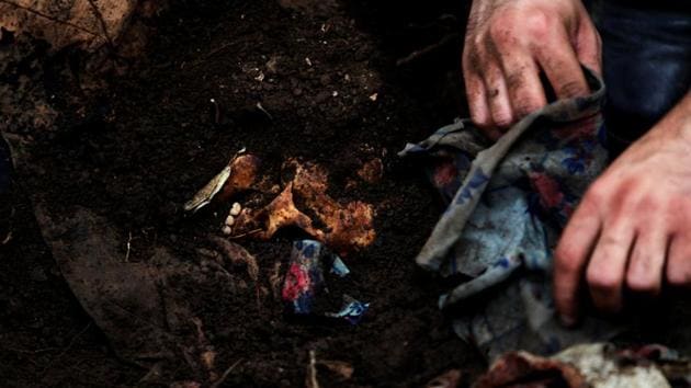 A human skull is unearthed as members of the forensic team and auxiliary workers exhume a grave at the site of the EL Mozote massacre. (Jose Cabezas / Reuters)