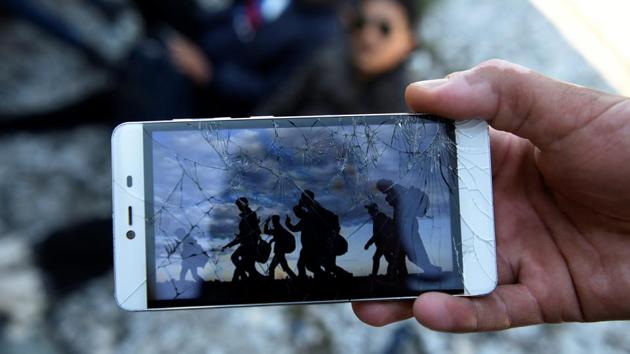 An Algerian migrant shows a picture on his mobile of fellow migrants walking in Macedonia. According to the migrant, his mobile phone was broken by Macedonian police when he was arrested and returned to Greece. (Alexandros Avramidis /Reuters) An Algerian migrant shows a picture on his mobile of fellow migrants walking in Macedonia. According to the migrant, his mobile phone was broken by Macedonian police when he was arrested and returned to Greece. (Alexandros Avramidis /Reuters)
