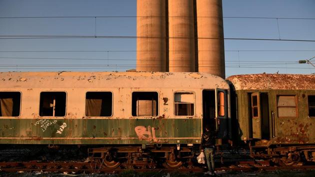 An Algerian migrant carries food in a plastic bag outside an abandoned railway wagon used as a shelter by stranded migrants . (Alexandros Avramidis /Reuters) An Algerian migrant carries food in a plastic bag outside an abandoned railway wagon used as a shelter by stranded migrants . (Alexandros Avramidis /Reuters)