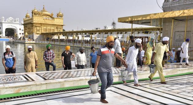 SGPC workers and devotees roll out mats and cool the floor with water from the sacred sarovar (pond) in the parikarma (circumambulation) of the Golden Temple as the summer is already close to its peak in Amritsar on Friday, April 21. (Gurpreet Singh/HT)