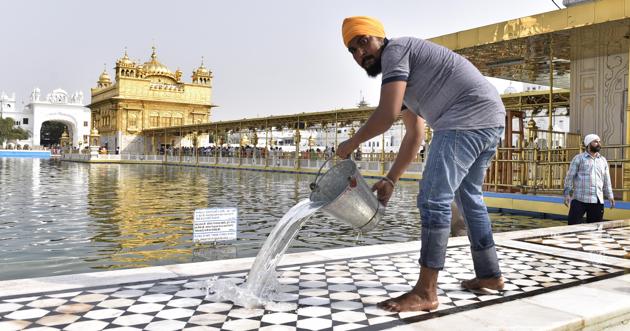 SGPC workers and devotees roll out mats and cool the floor in the parikarma (circumambulation) of the Golden Temple as the summer is already close to its peak in Amritsar on Friday, April 21. (Gurpreet Singh/HT)