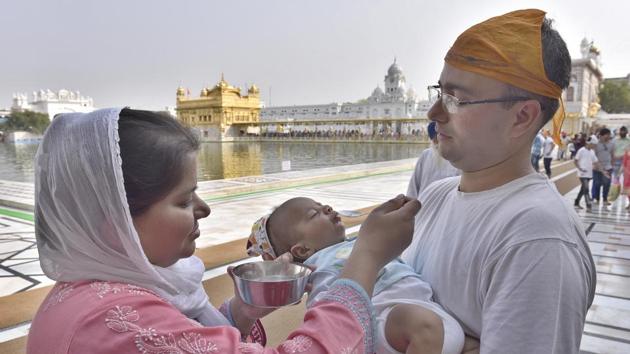 A couple gives water to an infant in the parikarma (circumambulation) of the Golden Temple in Amritsar on Friday, April 21. (Gurpreet Singh/HT)