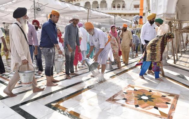 SGPC workers and devotees roll out mats and cool the floor with water and wipers in the parikarma (circumambulation) of the Golden Temple as the summer is already close to its peak in Amritsar on Friday, April 21. (Gurpreet Singh/HT)