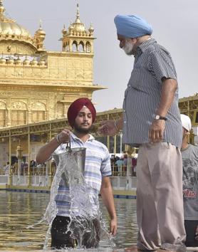 SGPC workers and devotees roll out mats and cool the floor with water from the sacred sarovar (pond) in the parikarma (circumambulation) of the Golden Temple as the summer is already close to its peak in Amritsar on Friday, April 21. (Gurpreet Singh/HT)