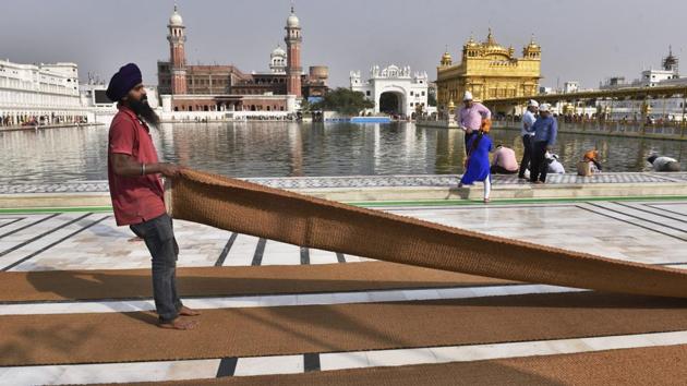 SGPC workers and devotees roll out mats and cool the floor with water and wipers in the parikarma (circumambulation) of the Golden Temple as the summer is already close to its peak in Amritsar. (Gurpreet Singh/HT)