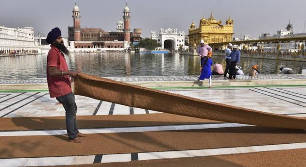 SGPC workers and devotees roll out mats and cool the floor with water from the sacred sarovar (pond) in the parikarma (circumambulation) of the Golden Temple as the summer is already close to its peak in Amritsar on Friday, April 21. (Gurpreet Singh/HT)