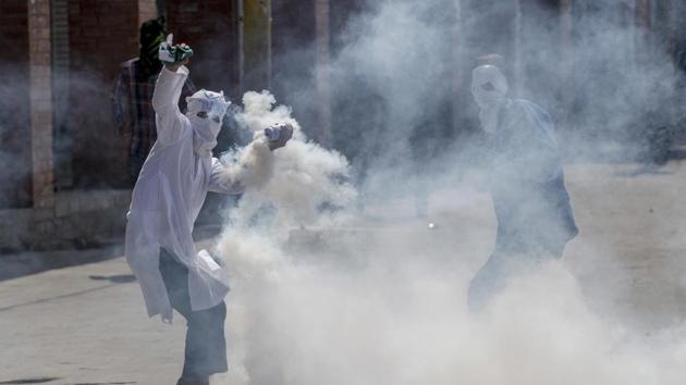 A masked Kashmiri protester throws an exploded tear gas shell back at Indian police during a protest in Srinagar on April 21.(AP Photo)