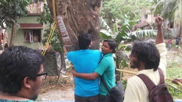 Students hugging a tree and shouting slogans on NH112 as the administration gets ready to fell it. (Facebook/Agnishwar Chakraborty) Students hugging a tree and shouting slogans on NH112 as the administration gets ready to fell it. (Facebook/Agnishwar Chakraborty)