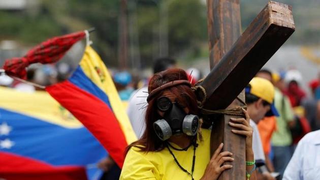 An opposition supporter carrying a cross attends a rally. (Christian Veron/Reuters) An opposition supporter carrying a cross attends a rally. (Christian Veron/Reuters)