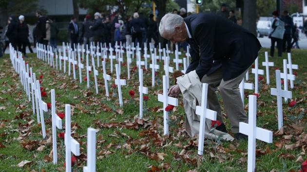 A man places a poppy on a cross at the field of remembrance following the ANZAC Day dawn service in Christchurch, New Zealand. (Mark Baker/AP)