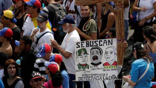 Opposition supporters carry a placard depicting (L-R) Venezuela's Defense Minister Vladimir Padrino Lopez, Venezuela's President Nicolas Maduro and Venezuela's Supreme Court President Maikel Moreno that reads "Wanted" during a rally. (Marco Bello/REUTERS) Opposition supporters carry a placard depicting (L-R) Venezuela's Defense Minister Vladimir Padrino Lopez, Venezuela's President Nicolas Maduro and Venezuela's Supreme Court President Maikel Moreno that reads "Wanted" during a rally. (Marco Bello/REUTERS)