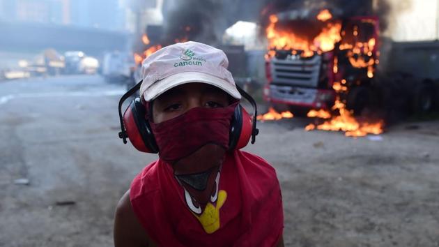 A hooded young boy is pictured near burning trucks during a demonstration by Venezuelan opposition activists. Riot police fired rubber bullets and tear gas to break up one of the first rallies in eastern Caracas early Monday while other groups were gathering elsewhere, the opposition said. (Ronaldo Schemidt/AFP) A hooded young boy is pictured near burning trucks during a demonstration by Venezuelan opposition activists. Riot police fired rubber bullets and tear gas to break up one of the first rallies in eastern Caracas early Monday while other groups were gathering elsewhere, the opposition said. (Ronaldo Schemidt/AFP)
