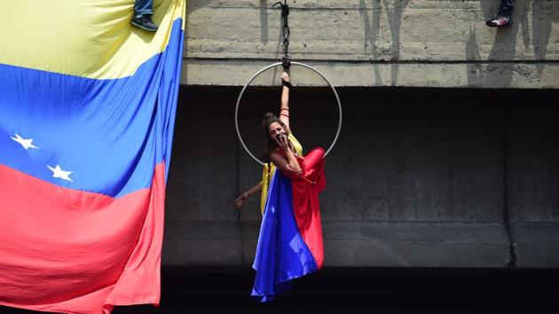 A Venezuelan opposition activist hangs from an overbridge as she takes part in a massive demonstration in Caracas. (Ronaldo Schemidt/AFP) A Venezuelan opposition activist hangs from an overbridge as she takes part in a massive demonstration in Caracas. (Ronaldo Schemidt/AFP)