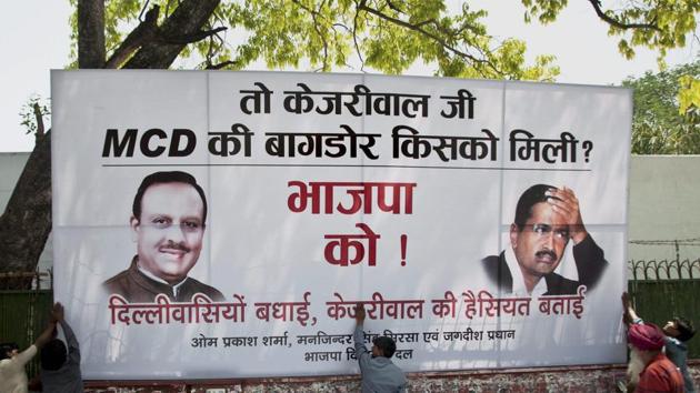 Workers put up a hoarding outside Delhi BJP headquarters in New Delhi on Wednesday after the party won the MCD elections.(PTI)