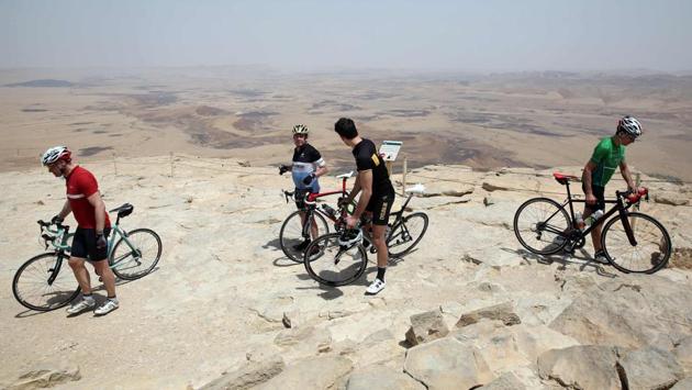 Foreign and Israeli cyclists stand on the cliff of Machtesh Ramon crater near Mitzpe Ramon city in the southern Israeli Negev desert. (MENAHEM KAHANA / AFP)