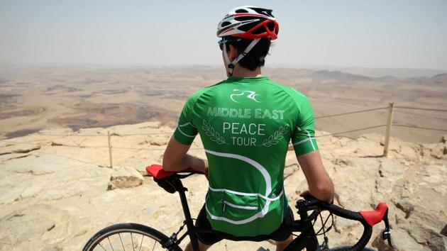 A cyclist stands on the cliff of the Machtesh Ramon crater, near the town of Mitzpe Ramon in the southern Israeli Negev desert, after riding on the fourth day of the Middle East Peace Tour. (MENAHEM KAHANA / AFP)