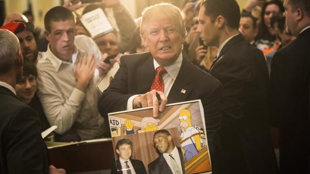 Donald Trump holds depictions of himself on, "The Simpsons" and a photo with boxer Mike Tyson, given to him by an attendee during a Presidential campaign stop at the Radisson Hotel in Nashua, N.H.(AP File Photo)