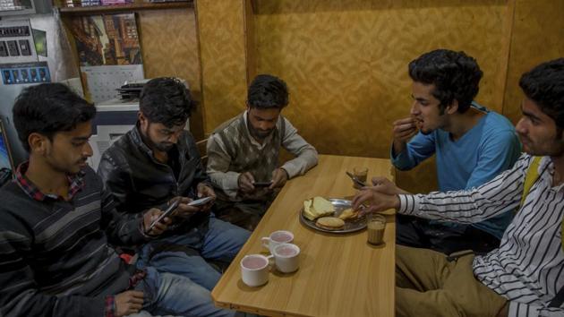 Kashmiri students browse internet on their mobile phones as they sits inside a restaurant in Srinagar, on April 26, 2017. Internet service providers were ordered to block 16 social media sites, including Facebook and Twitter, and popular online chat applications for one month on Wednesday.(AP Photo)