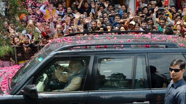 Prime Minister Narendra Modi greeting people from his vehicle ahead of his rally in Shimla on Thursday.(Deepak Sansta/HT Photo)